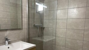 Ein modernes Badezimmer mit Waschbecken, Spiegel und Duschkabine.