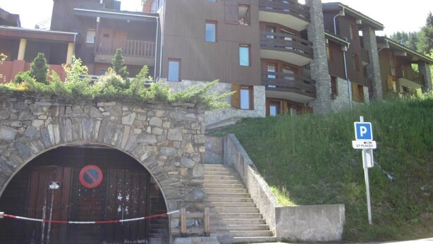Ein mehrstöckiges Hotel mit Balkonen, einem Portal aus Stein und einem Parkschild, das 97 Stellplätze anzeigt.