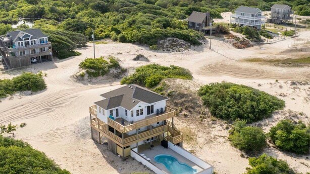 A beachfront property with a two-story house featuring a balcony and a swimming pool. - Blue Moon - 4x4 Carova Beach, Ocean View, Pool, Hot Tub, Rec Room, Pool Table (4x4 - Carova NC)