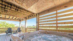 A wooden deck with a hot tub, chairs, and a view of the ocean. - Blue Moon - 4x4 Carova Beach, Ocean View, Pool, Hot Tub, Rec Room, Pool Table (4x4 - Carova NC)