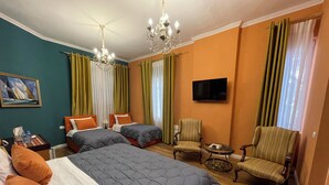 A hotel room with two beds, a TV, a chair, and a table.