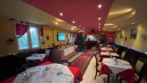 A restaurant with tables set for dining, a Christmas tree, and holiday decorations.