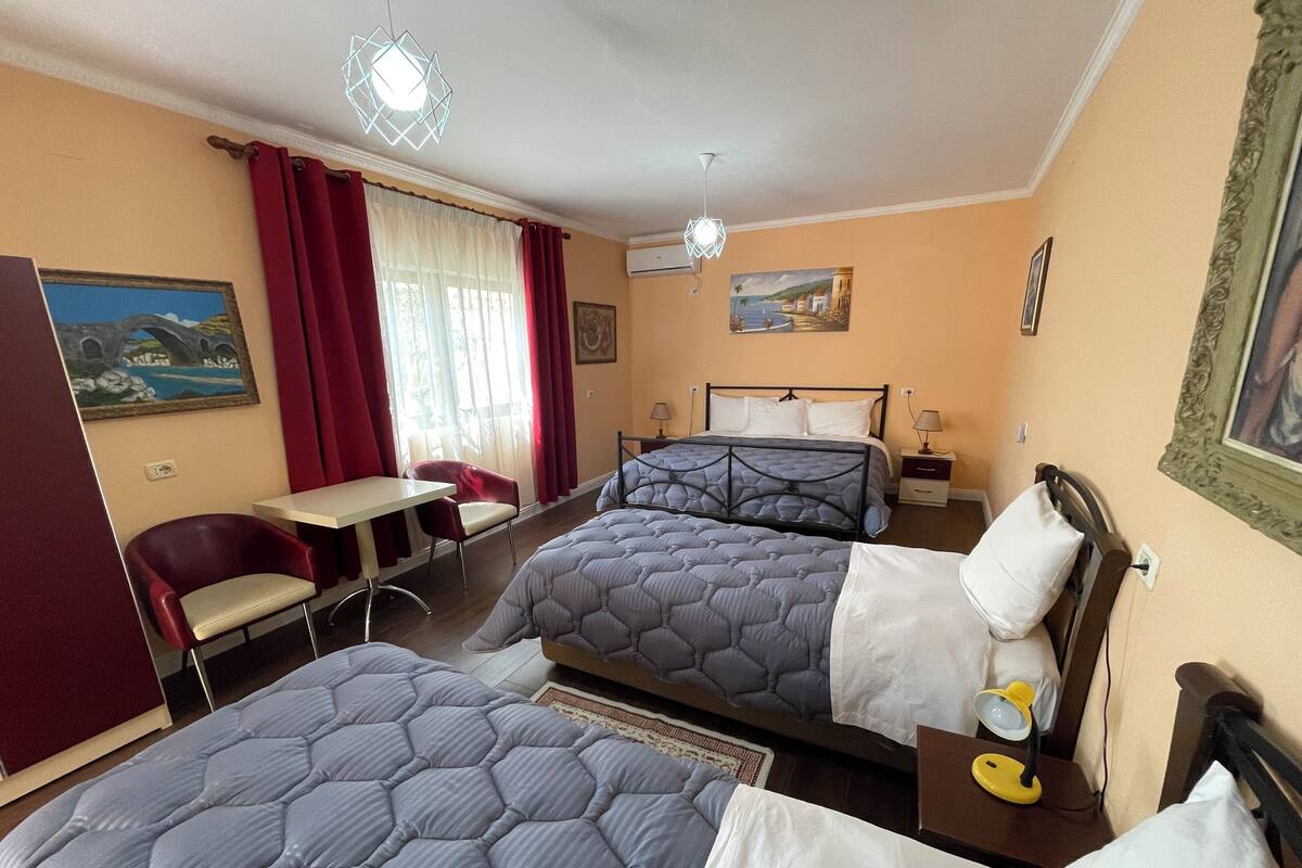 Une chambre d’hôtel avec deux lits, un bureau, une chaise et un tableau au mur.