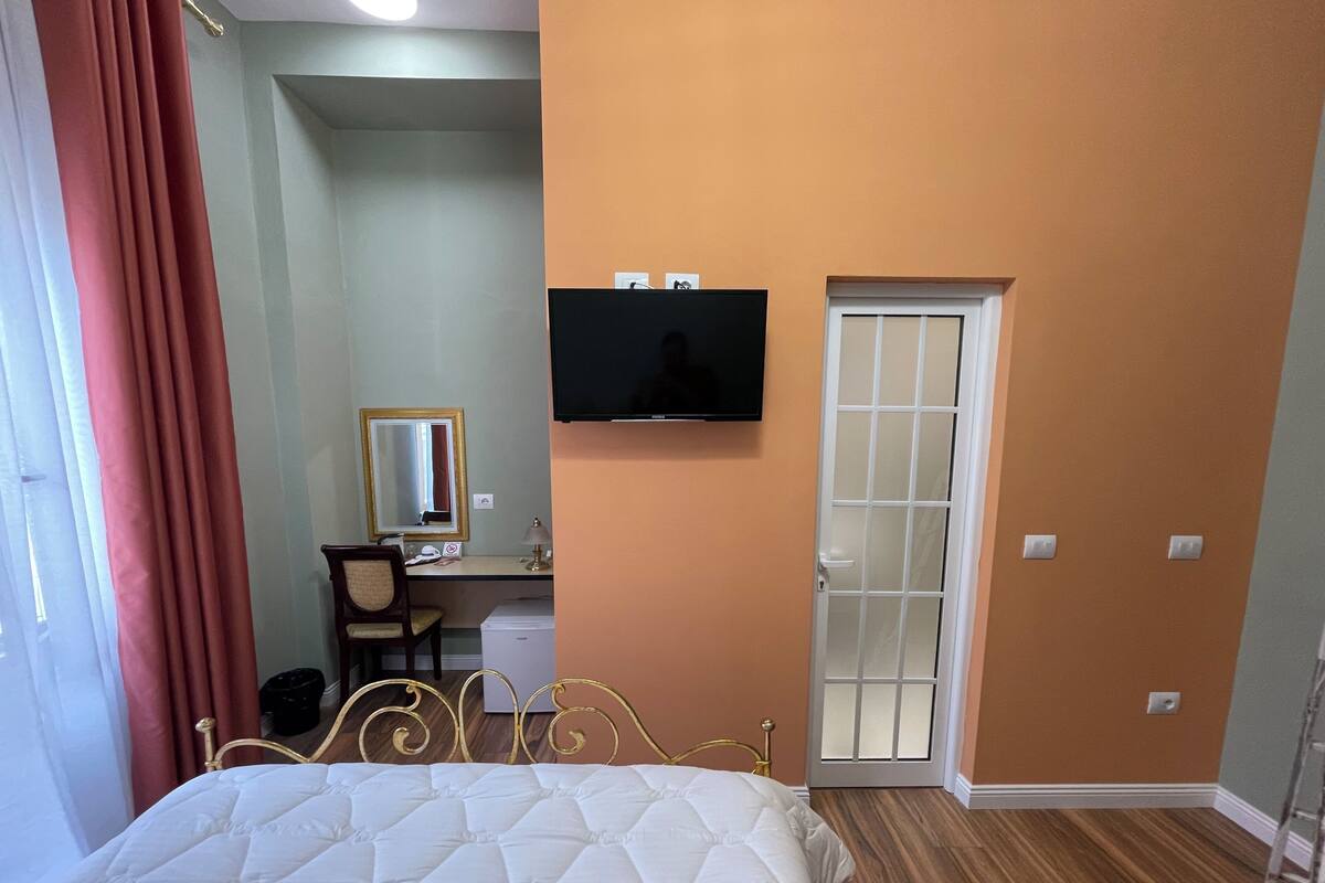 Une chambre d’hôtel comprenant un lit, un bureau avec une chaise, une télévision et une porte dotée d’un panneau en verre dépoli.