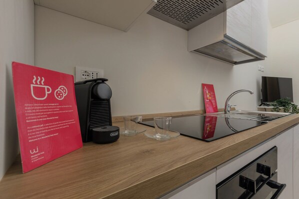 A modern kitchen with a coffee machine, a glass of water, and a red sign. - Ai Portici di Susa by Wonderful Italy (Turin)