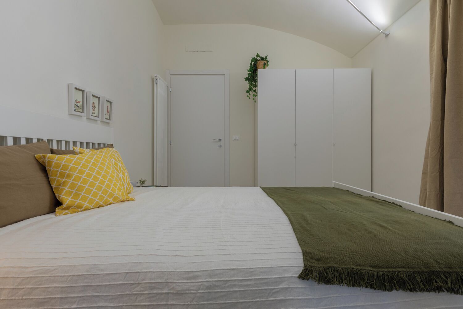 A bedroom with a bed, a wardrobe, and a door.