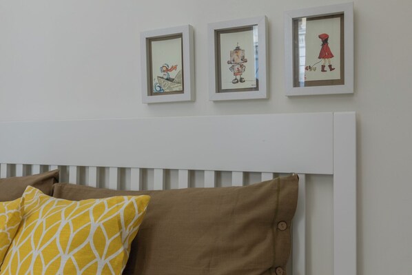 A bedroom with a white headboard, three framed artworks, and two pillows with geometric patterns. - Ai Portici di Susa by Wonderful Italy (Turin)