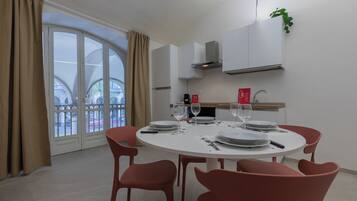 A dining area with a round table, red chairs, and a view of a building through a glass door.