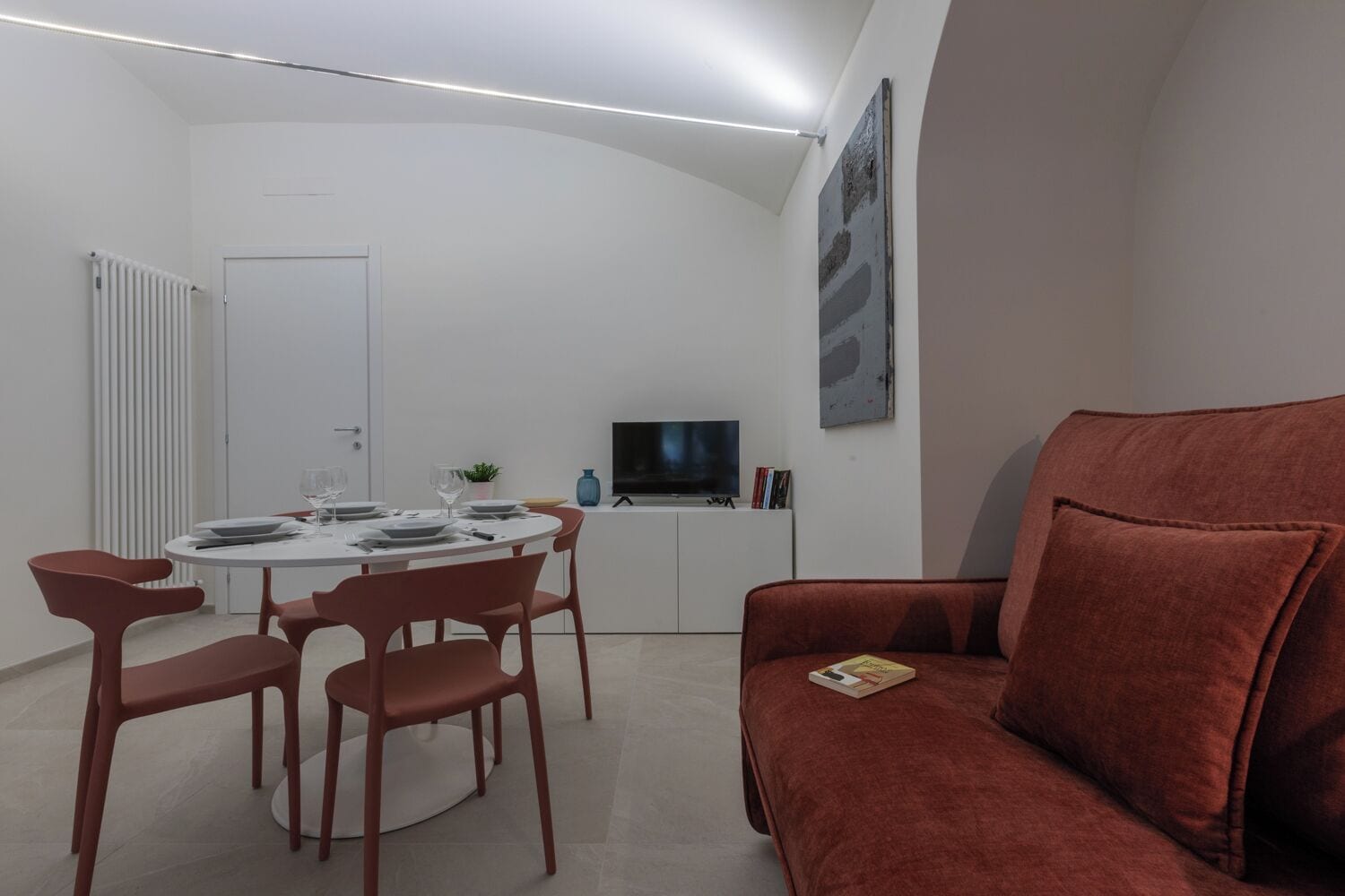Un espace de vie compact comprenant un coin repas, un canapé et un téléviseur.