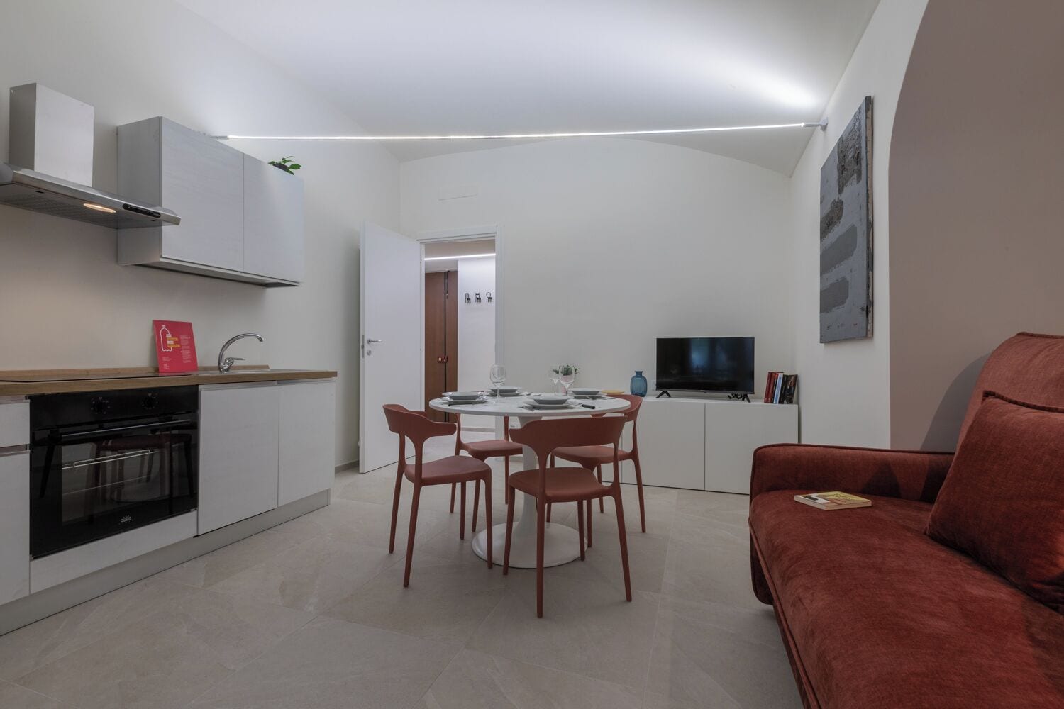 A compact living space with a kitchen, dining area, and a red sofa.