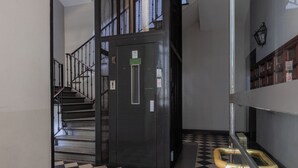 A staircase with a black and white checkered floor, a metal elevator, and a staircase railing. - Ai Portici di Susa by Wonderful Italy (Turin)