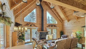 A log cabin interior with a dining area, seating, and a fireplace.