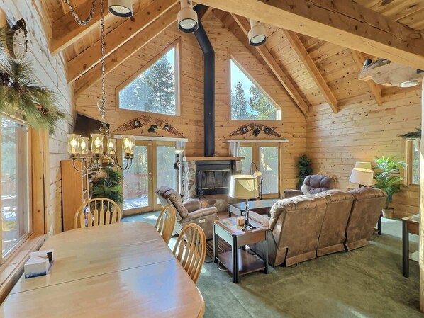 A log cabin interior with a dining area, seating, and a fireplace.
