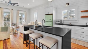 A modern kitchen with a central island, white cabinetry, and a green refrigerator. - Incredible Coastal Getaway w/ Private Pool Near Sav + Beach by Lucky Savannah (Thunderbolt)