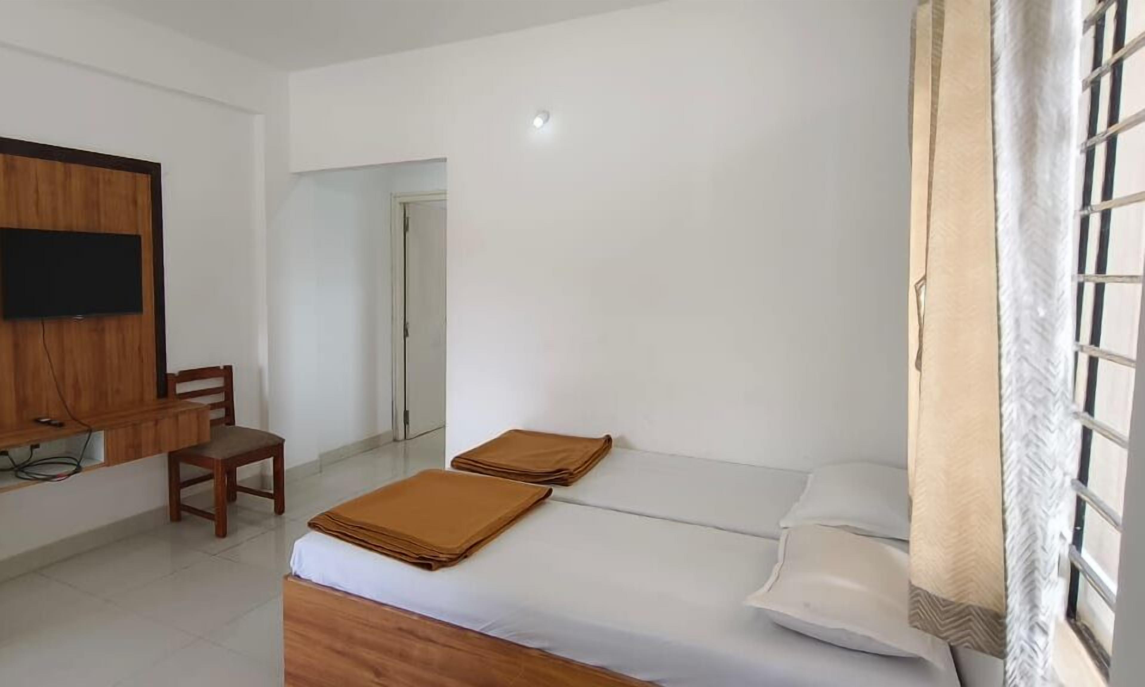 A bedroom with a bed, a desk, and a TV mounted on the wall.