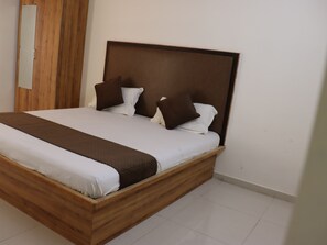 A single-bed room with a wooden headboard, white bedding, and two brown pillows. - Sgr Luxury Homes (Anekal)