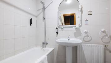 Ein modernes Badezimmer mit Badewanne, Waschbecken, Spiegel und Dusche.