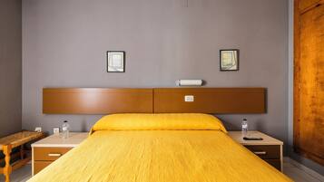 Una habitación de hotel con una cama, mesitas de noche, un banco y dos cuadros en la pared.