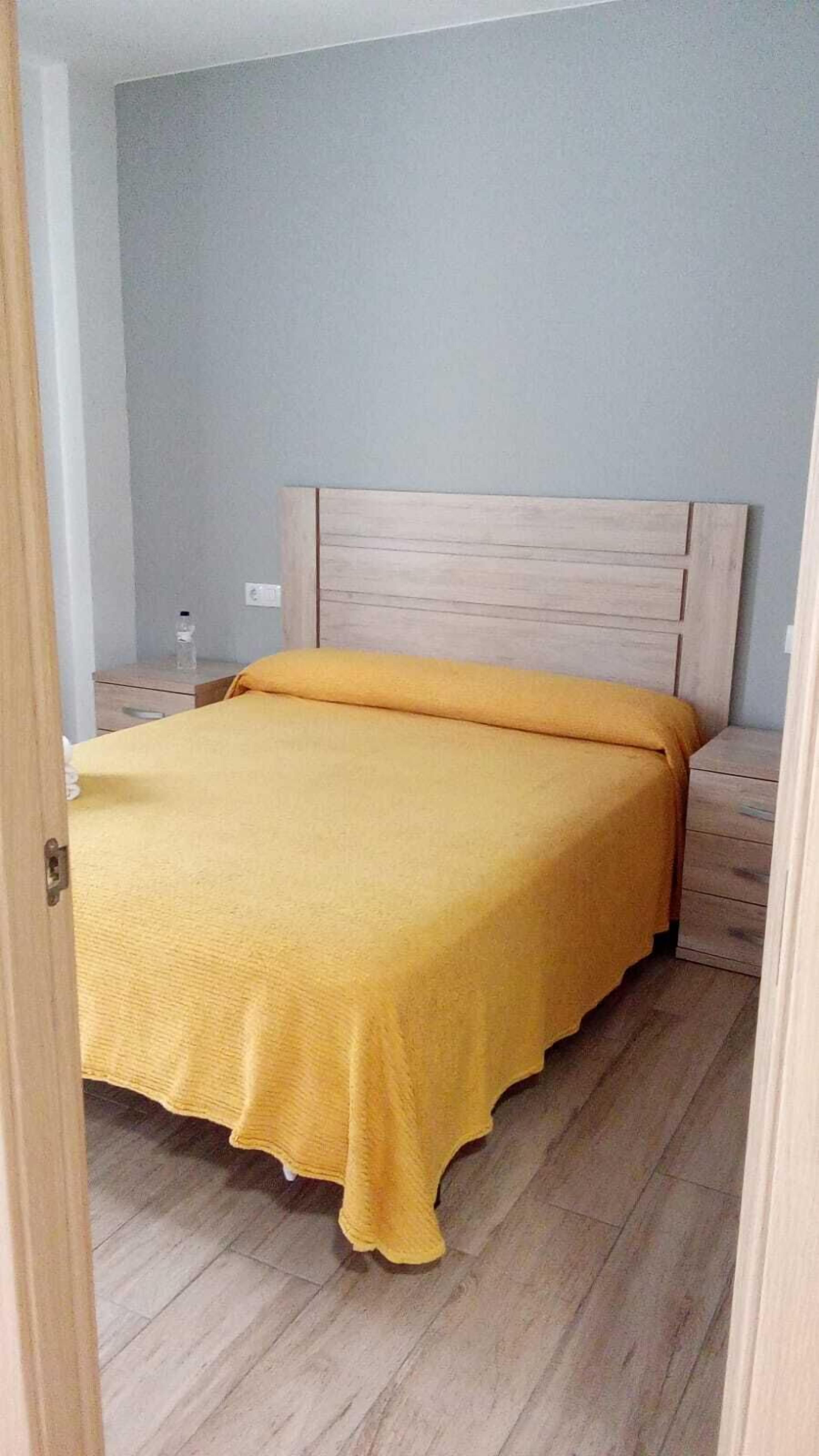 A bedroom with a bed, a nightstand, and a wall socket.