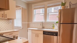 A modern kitchen with white cabinetry, a stainless steel refrigerator, and a dishwasher.