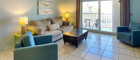A living room with a sofa, two armchairs, a coffee table, and a sliding glass door leading to an outdoor area.