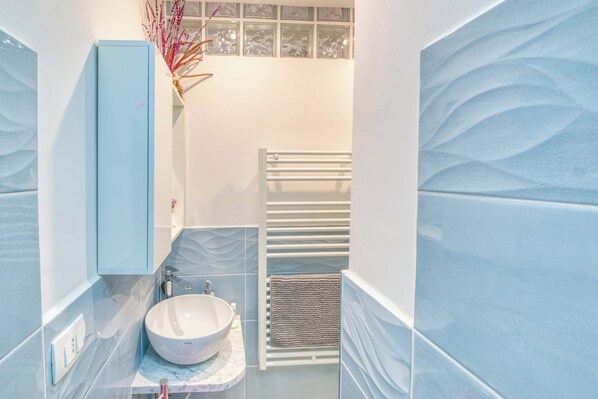 A bathroom with a white sink, a blue cabinet, and a towel rack.