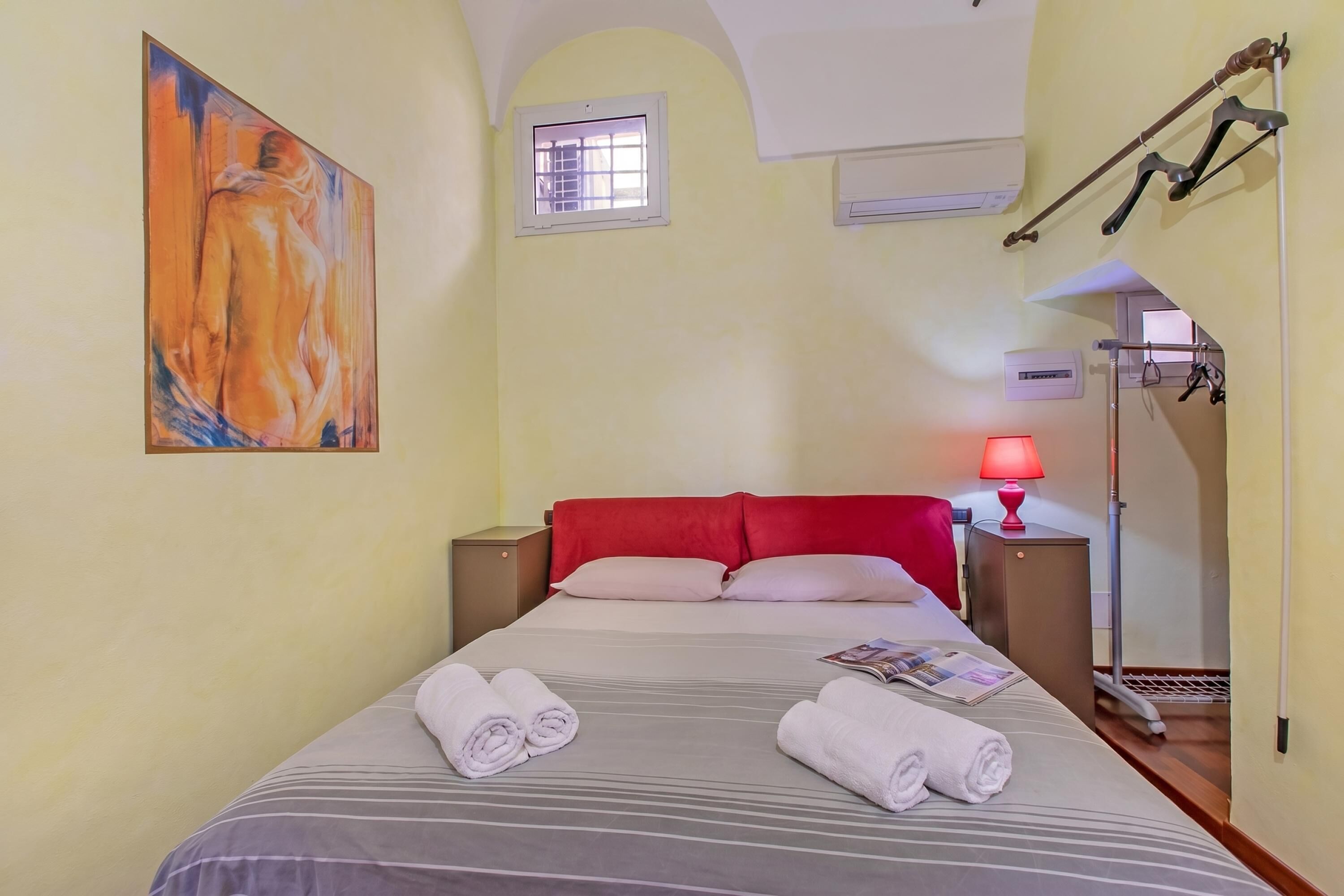 Habitación de hotel con cama, un cuadro en la pared, una ventana y una lámpara.