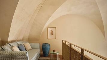 A cozy room with a patterned sofa, a large vase, and a framed picture on the wall.