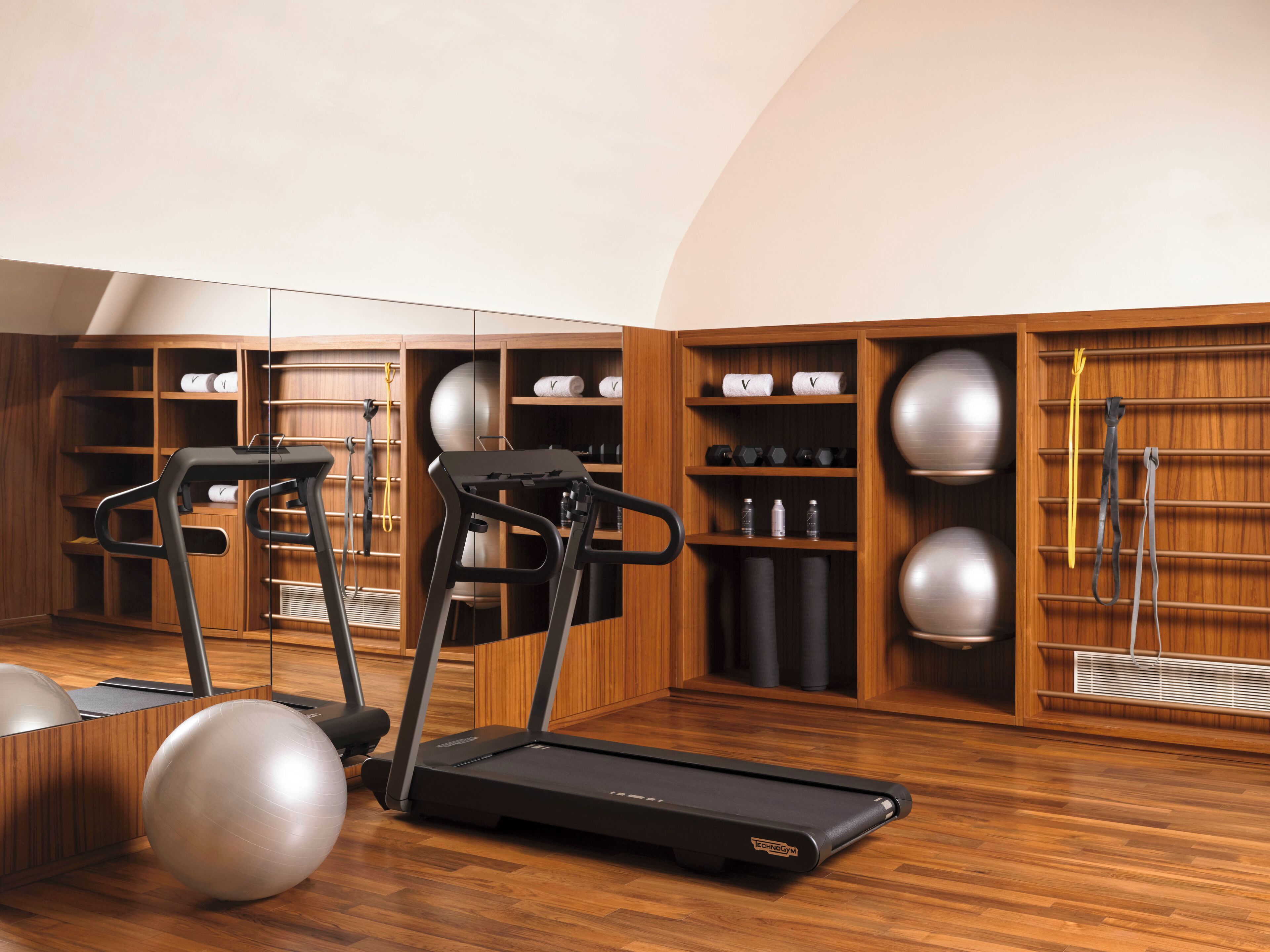 Una palestra in casa con tapis roulant, palle da ginnastica e rastrelliera per pesi.