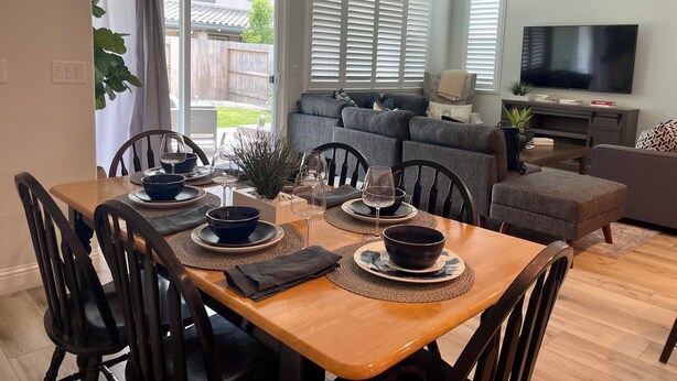 Een eetgedeelte met een houten tafel voor vier personen, omringd door zwarte stoelen.