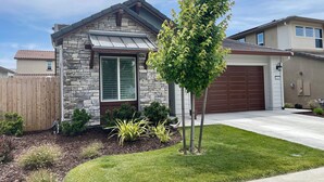 Een gelijkvloers huis met een gevel van natuursteen, een garage en een verzorgd gazon.