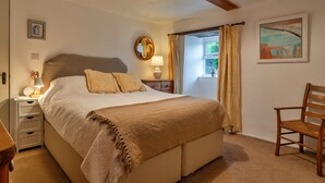 A bedroom with a bed, bedside table, lamp, and a chair. - The Noel at Lesceave (Praa Sands)