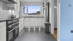A modern kitchen with a large window, stainless steel appliances, and a view of the outdoors.