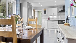 A modern kitchen with white cabinets, a black stove, and a dining area with a wooden table and chairs.