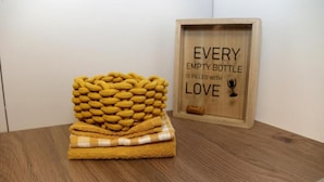 Una caja de madera con una frase motivacional y un objeto tejido amarillo sobre una superficie de madera.