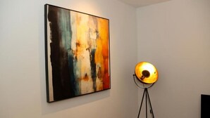 Una habitación con un cuadro abstracto grande en la pared y una lámpara de pie.