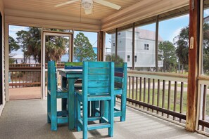 Enjoy dining or socializing in this covered outdoor space with a wooden table and chairs, surrounded by large windows offering views of the surrounding landscape.