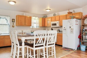 Enjoy meals at the dining table with four chairs, a refrigerator, and microwave.