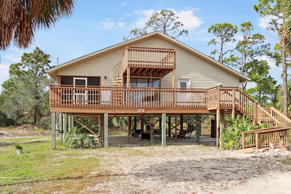 Stands on wooden stilts, this two-story building features a balcony and a grassy lawn.