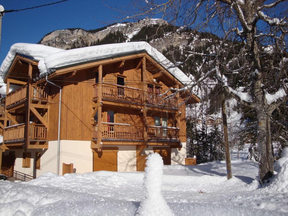 Een houten chalet met meerdere balkons, omringd door besneeuwde bergen.