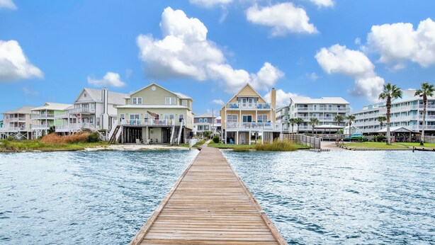 A wooden pier leading to a beachfront hotel with multiple balconies and a clear sky. - Lagoon Front | Pet Friendly | Boat Launch, Pier and Beach Access (Gulf Shores)