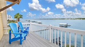 A wooden deck with blue Adirondack chairs overlooking a marina with docks and boats. - Lagoon Front | Pet Friendly | Boat Launch, Pier and Beach Access (Gulf Shores)