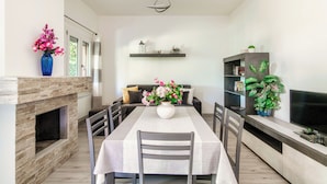 Un comedor moderno con chimenea, una mesa de comedor, sillas y un televisor sobre un mueble.