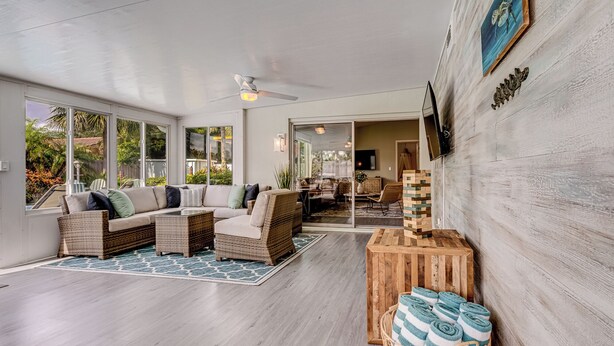 A spacious living area with a large sofa, wicker chairs, a wooden coffee table, and a jigsaw puzzle on a wooden table. - Gorgeous Home with Heated Pool Near Beaches (Seminole)