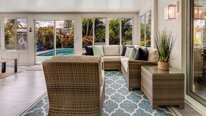 A spacious indoor area with a large wicker sofa, a small table, and a patterned rug. - Gorgeous Home with Heated Pool Near Beaches (Seminole)