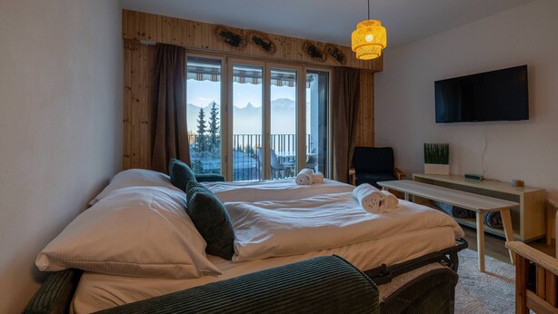 Een hotelkamer met twee bedden, een bureau, een stoel en een televisie.