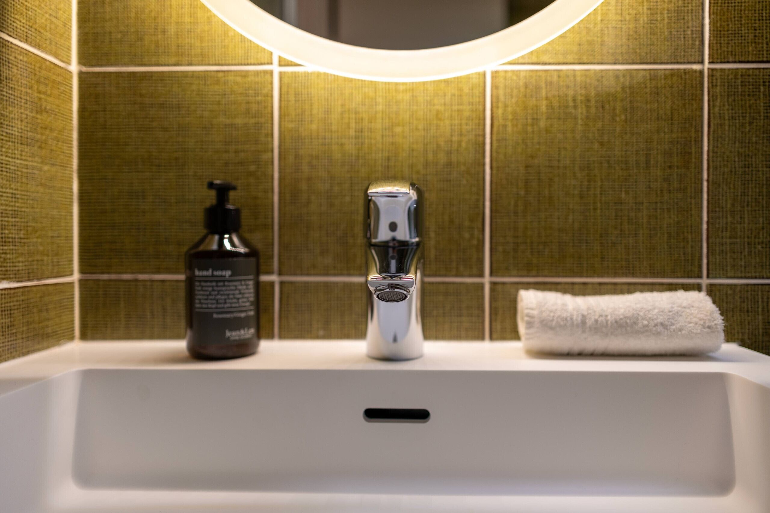 A bathroom sink with a hand soap dispenser and a towel.