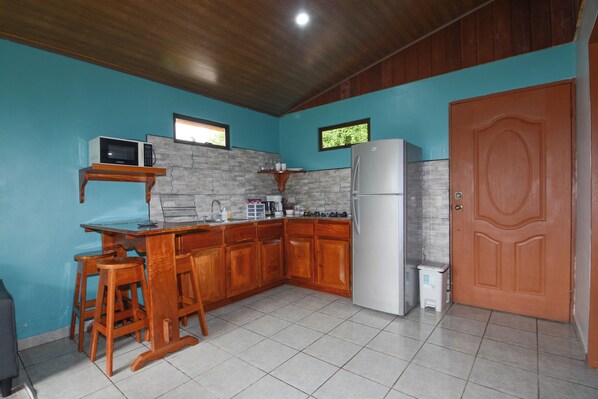 A kitchen with wooden cabinets, a microwave, a refrigerator, and a sink.