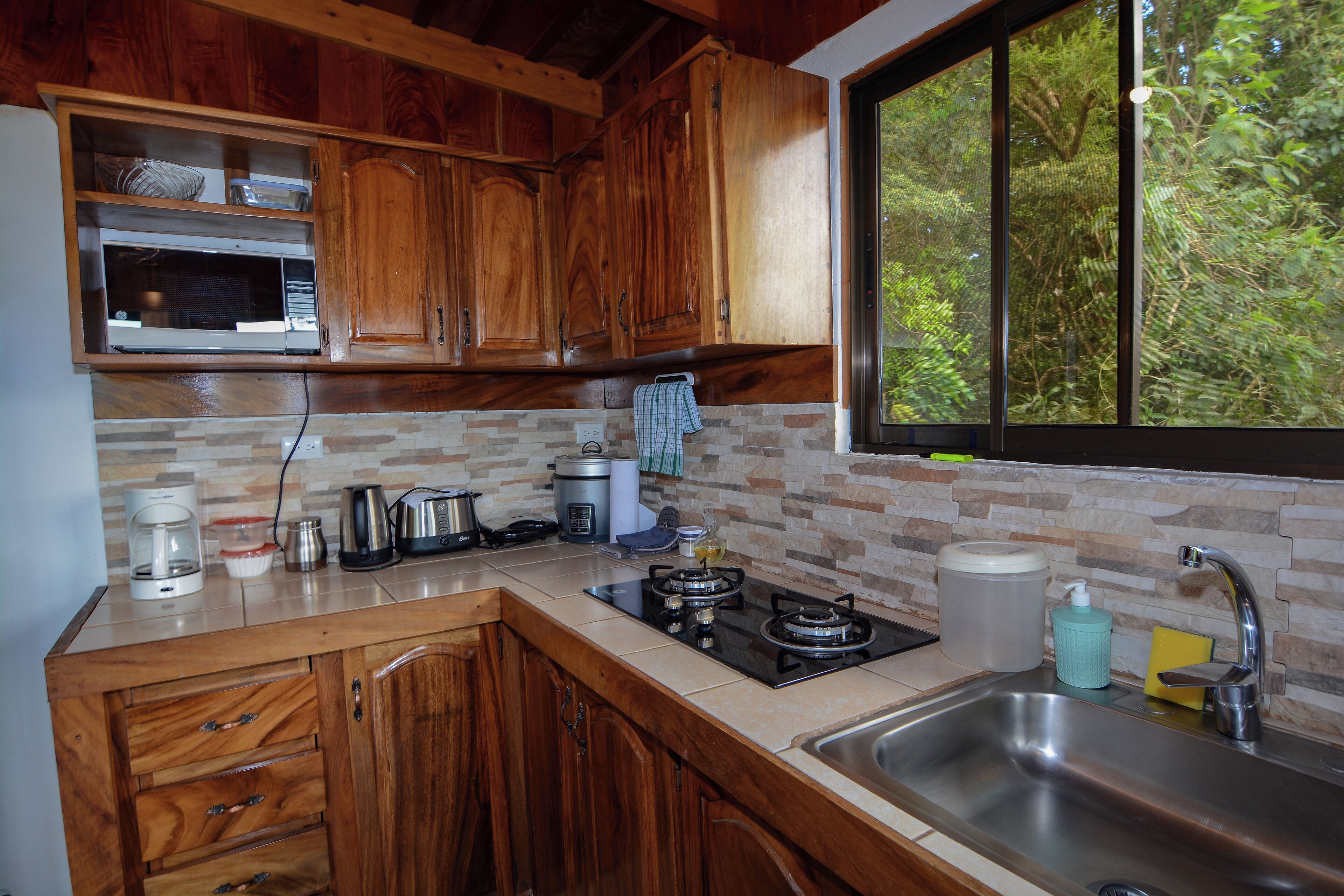 A kitchen with wooden cabinets, a microwave, a gas stove, and a sink.