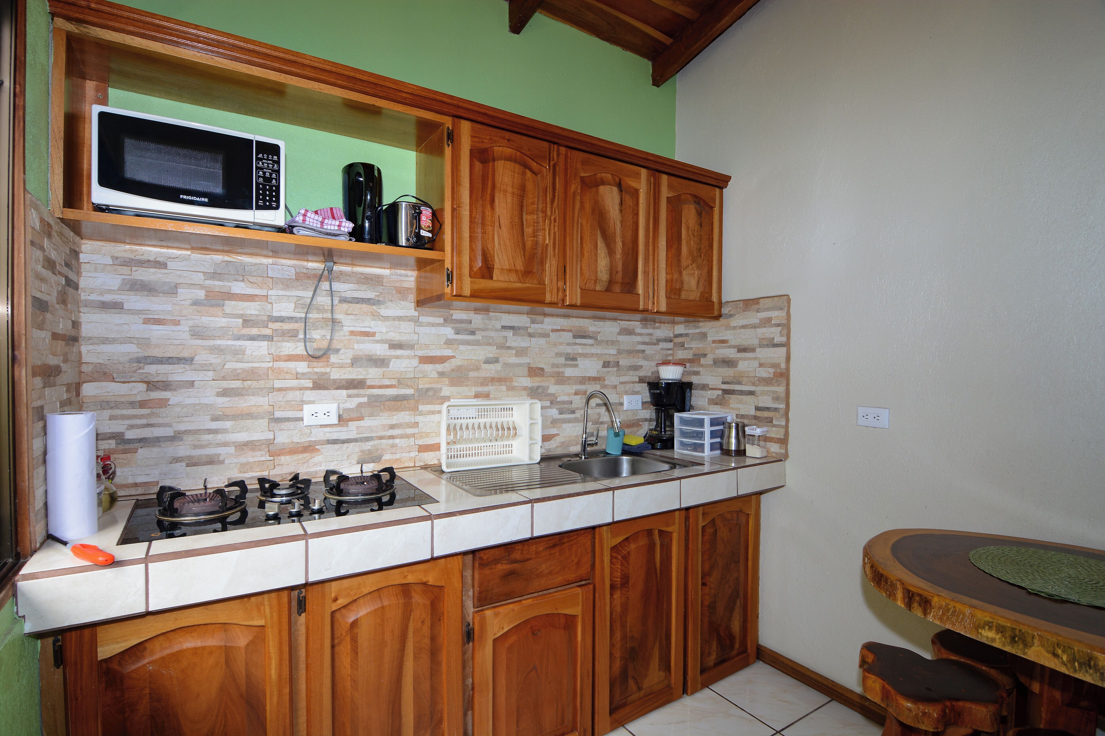 A kitchen with wooden cabinets, a microwave, a stove, and a sink.